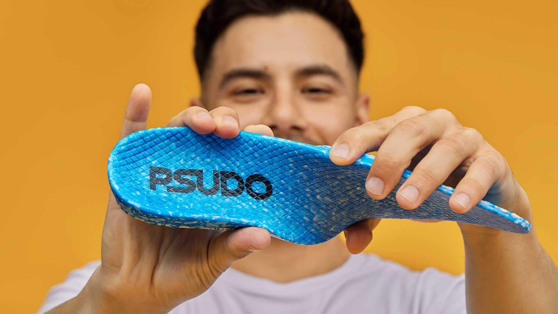 Product photography depicting slip-on PSUDO blu shoe insole being twisted by a man