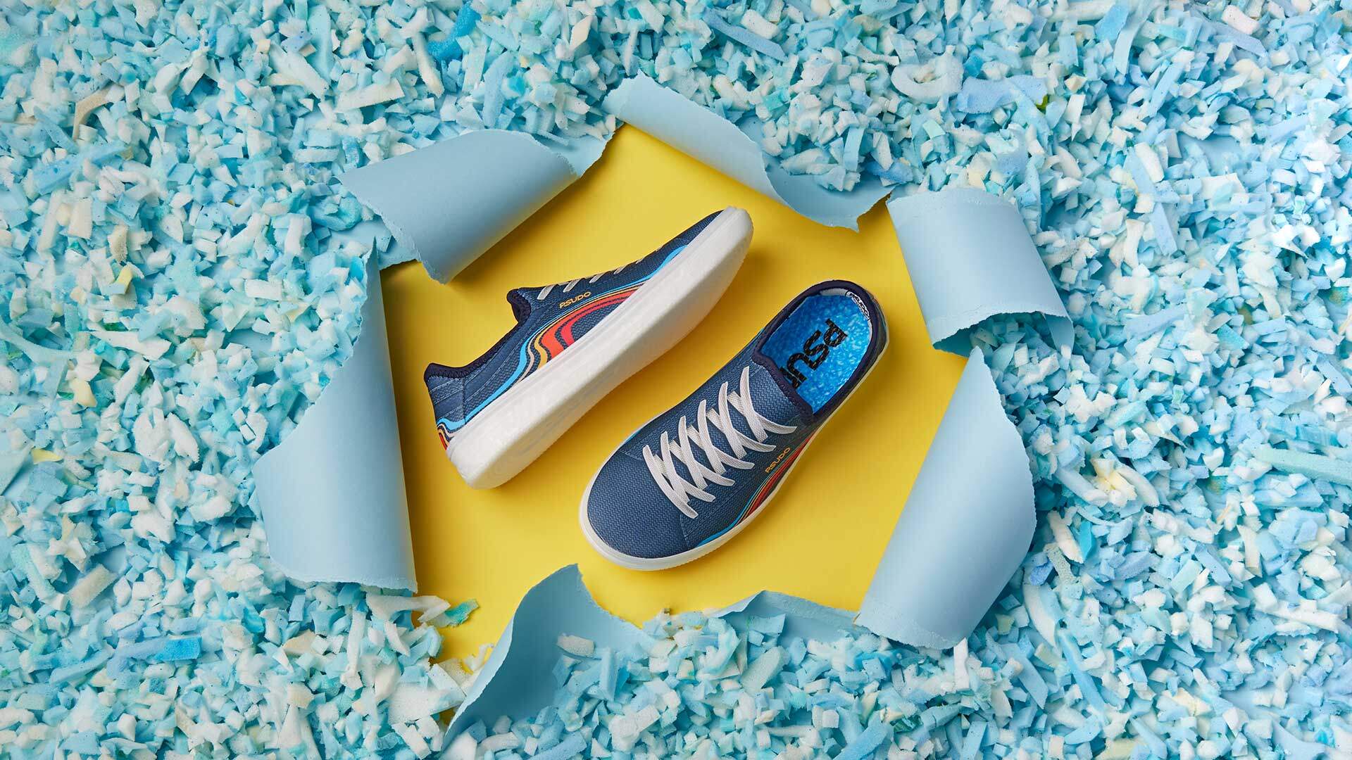 Product photography depicting slip-on PSUDO blu shoe bursting out of foam