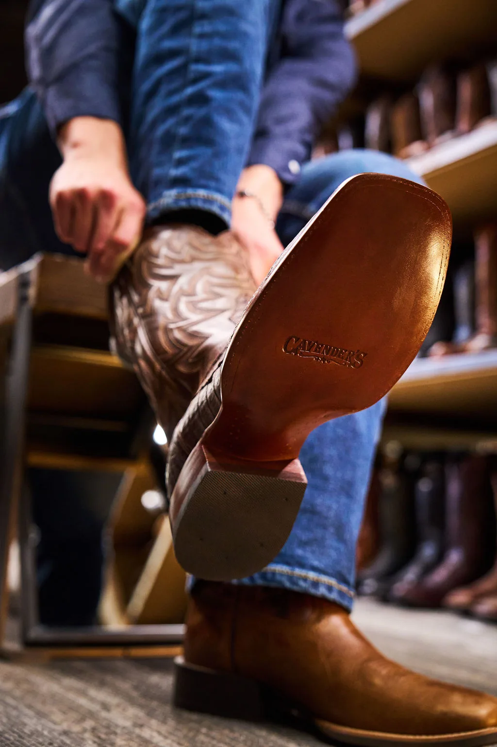 Cavender's boot being pulled on with Cavender's logo seen on the bottom of the boot